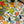 Close up of table top covered in Agrume Fruits tablecloth. The tablecloth background is white and the pattern  features lemons, limes, oranges, kiwis and leaves. Vibrants colors of orange, yellow and green.