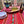 Decorative table setting with a colorful red tablecloth, wine glasses, plates, and a vase of flowers.
