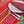 Decorative table setting with floral-patterned tablecloth. Pattern is stripes of olives, leaves, mimosa flowers and medallions in turquoise, green, blue, black and yellow on a vibrant red background. While plate, silver forks, coordinating red and blue napkin